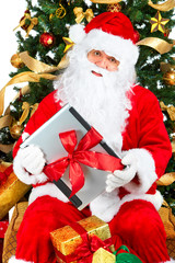 Smiling Santa, laptop, christmas tree. Over white background.