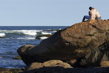 Paar sitzt auf einem Felsen am Meer