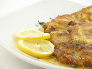 Chicken with a lemon sauce on a white plate