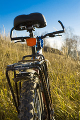 Sports bicycle on an autumn meadow against the blue sky