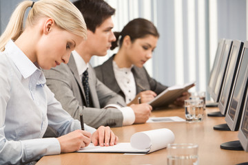 Young businesswoman making notes in her notepad