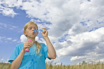 Children blowing bubbles on summer meadow