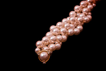 twisted strand of pearls on black with gold and diamonds