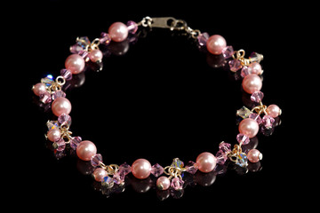 A pink beads bracelet isolated on black background.