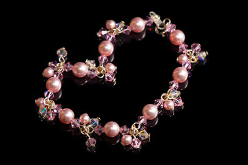 A pink beads bracelet isolated on black background.