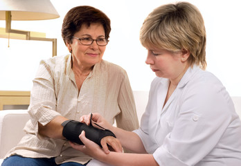 female doctor examining wrist of senior patient at home