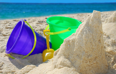 Sand buckets in beach sand next to gorgeous ocean water