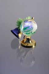 Little toy glassy globe with jingle bells on gray background