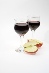 Isolated two goblets of red wine and slit apple