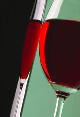 Glass and bottle of red wine on green background