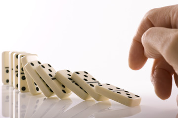 Line of dominos falling down after being pushed by finger