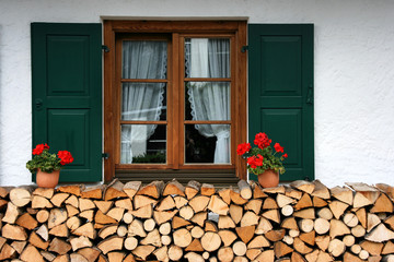 Window with flowers and chopped firewood in Mittenwald