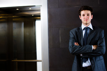 Portrait of satisfied young businessman in grey suit standing