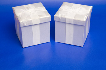 Two neatly wrapped gift boxes over blue.