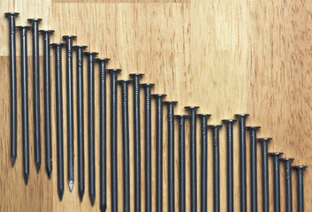 Declining Graph of Nails on a Wood Background.