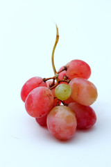 One small grape in the middle of a bunch of larger grapes.