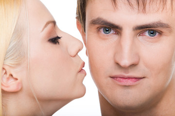 Handsome guy looking at camera with girl kissing him