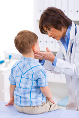 Senior female doctor examining little child boy.