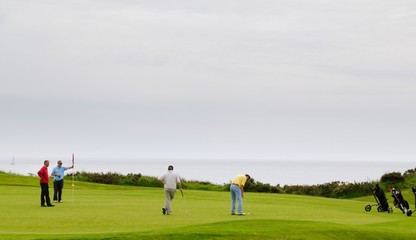 Obraz na płótnie Canvas Golfeurs sur un green en bord de mer