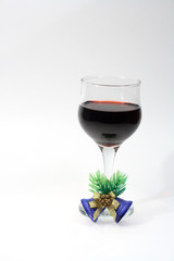 Goblet of red wine with little jingle bells on white background