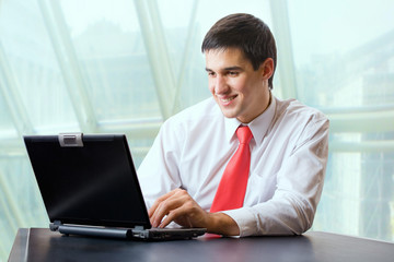 Fototapeta premium Young happy businessman or student on laptop