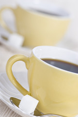 Two fresh cups of morning coffee with one lump of sugar.