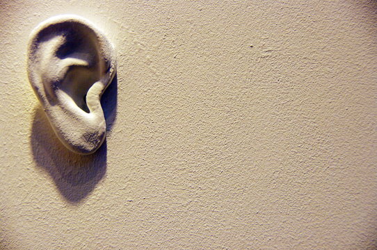 Chut... Les murs ont des oreilles.  Oreille sur un mur blanc