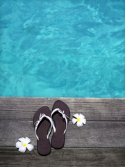 women sandals on a wooden floor with flowers near the water