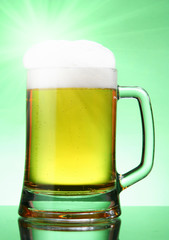 Mug of beer with glare over green background