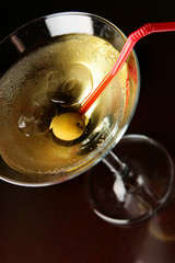 Cocktail glass with ice and olive close-up over black background