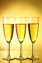 Three glasses of champagne over yellow background