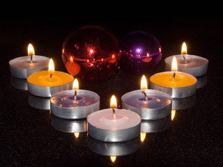 Burning candles and fur-tree toys on a black background