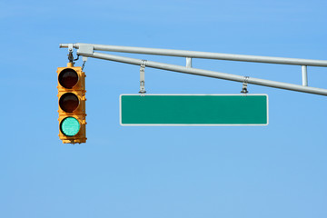 Green traffic signal light with sign on blue sky