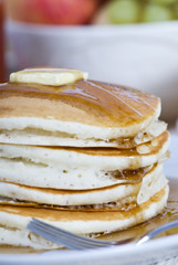 A pile of fresh pancakes with melted butter and syurp.