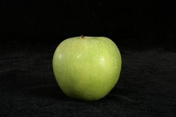 a wet green apple on black background