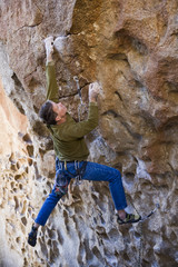 Climber clinging to an overhanging rock face.