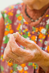 An old woman holding a pill in her hand - part of a series.