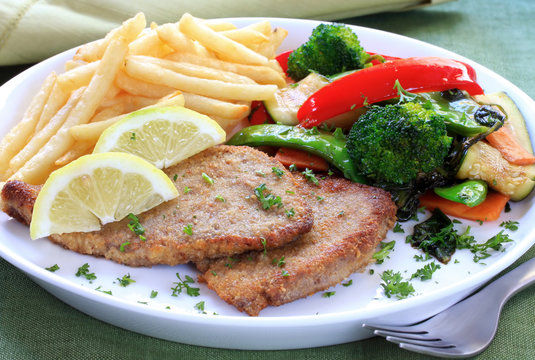Schnitzel with fries and colorful vegetables.