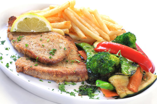Schnitzel with french fries and colorful vegetables.