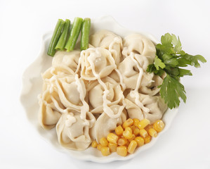 Pelmeni on a plate with asparagus, olives and a corn
