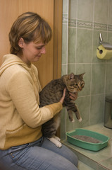 the Image of the girl showing to a cat its toilet