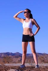 Female jogger with beautiful toned body shielding her eyes