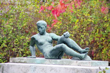 Fototapeta na wymiar Statue de femme en bronze allongée sur un socle de pierre