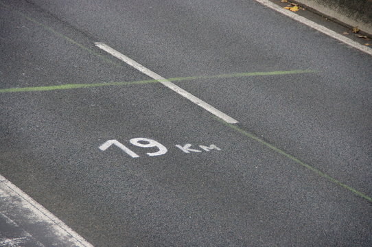 Fototapeta Km 19. 19 kilomètres peint sur route de goudron noir.