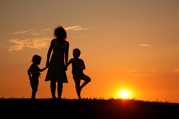 Fototapeta na wymiar Mother and children on sunset silhouette
