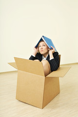 The woman in a business suit sitting in a cardboard box