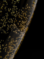 Macro of sparkling champagne against black background.