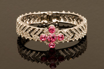 Obraz premium Bracelet with red stones on reflective background