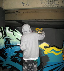 Jeune homme dessinant un graffiti sur un mur.