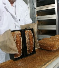 baecker holt brot aus dem backofen